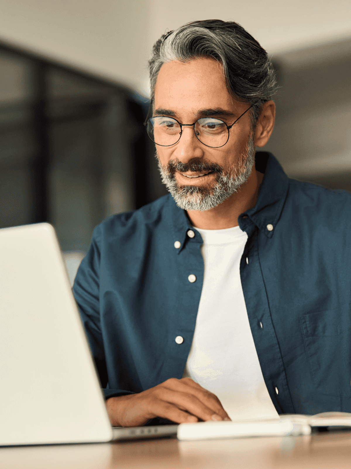 Man inside an office, looking at his laptop