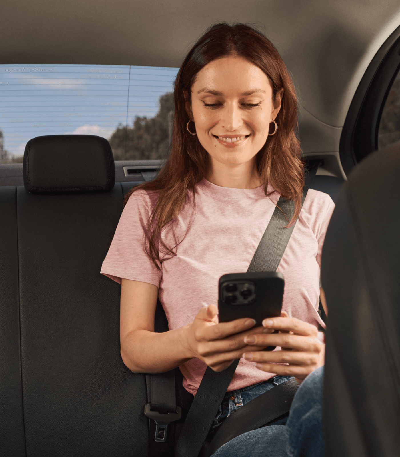 woman in taxi using freenow app on phone