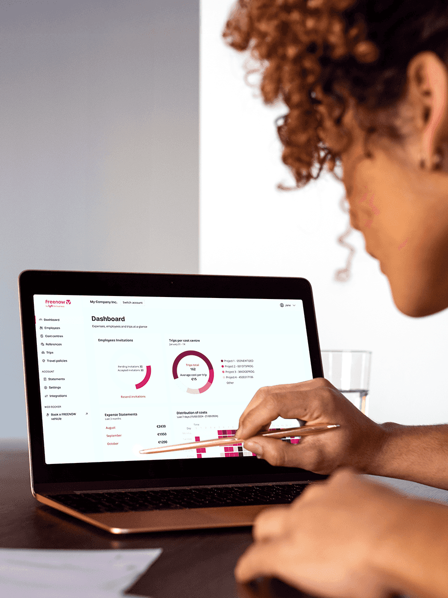 Business traveller sitting in taxi on way to a business trip holding her mobile phone on the FREENOW app