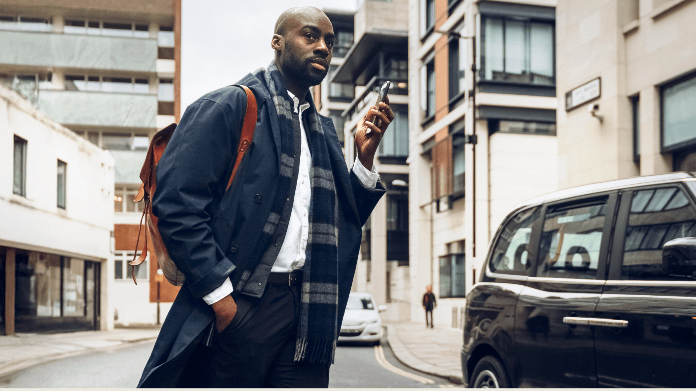 man holding phone standing outside black cab