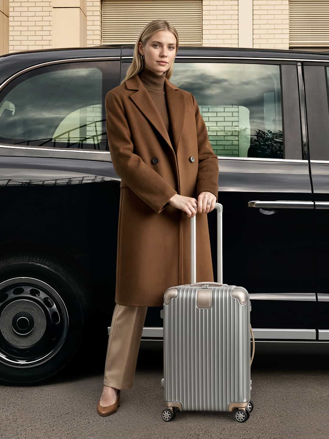 woman outside black cab holding luggage