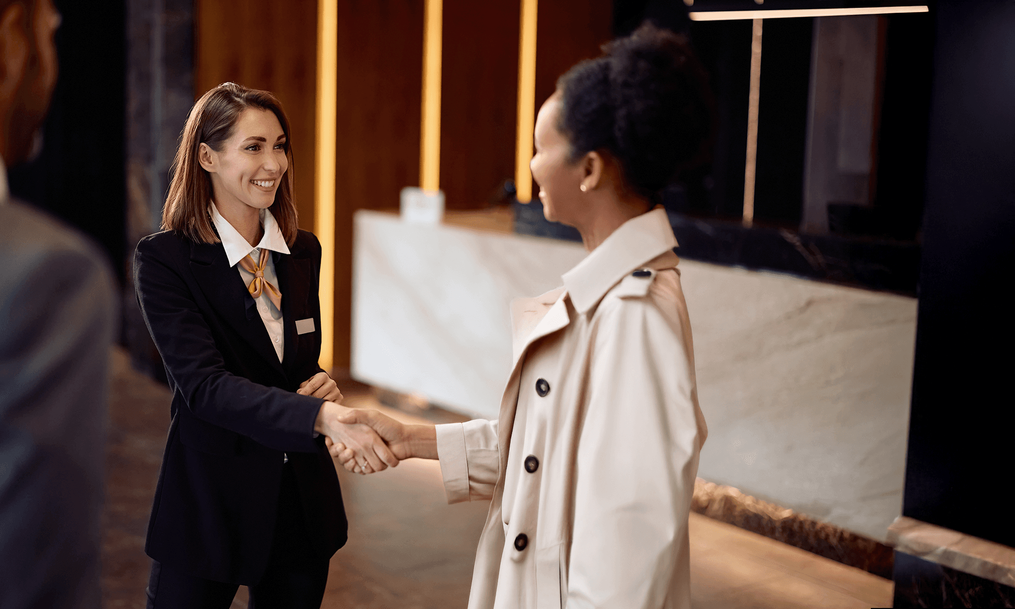 Receptionist speaking to guest at desk and ordering a taxi on their computer using the FREENOW Web Booker